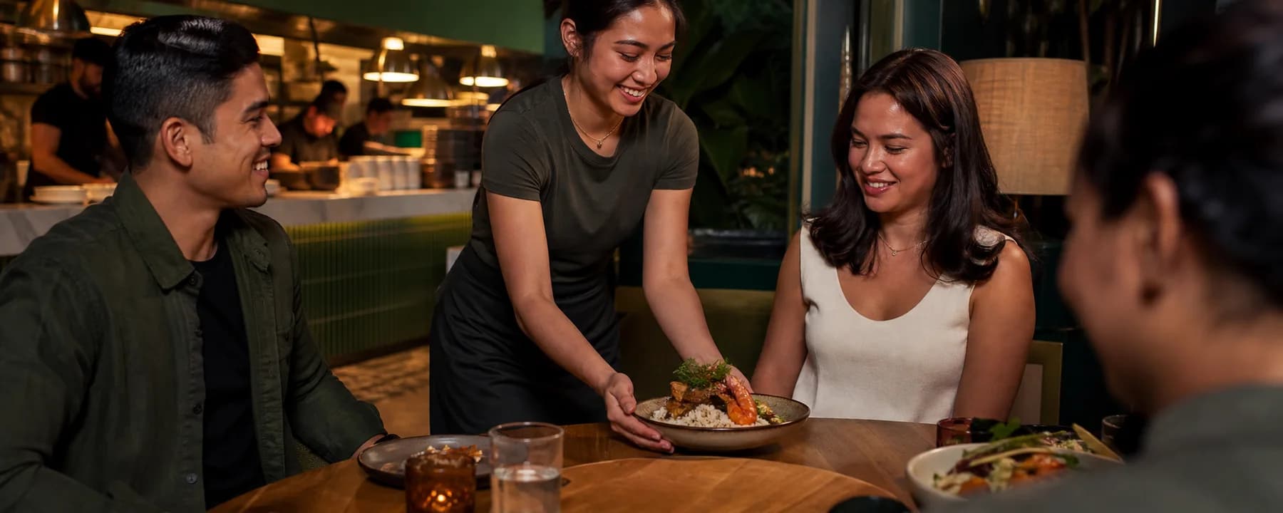 A restaurant server placing a freshly prepared meal at a guest table
